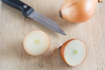 Zwiebeln mit einem Messer liegen auf einem Holzbrett.