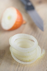 Zwiebeln mit einem Messer liegen auf einem Holzbrett.