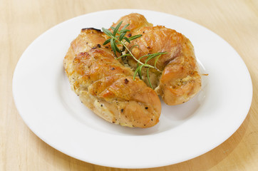Spicy baked chicken breast with rosemary entirely on a plate