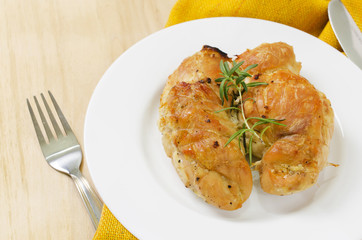 Spicy baked chicken breast with rosemary entirely on a plate