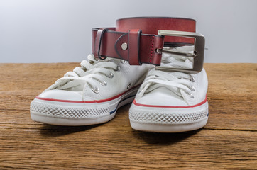 white sneakers shoe and brown leather belt on wooden board