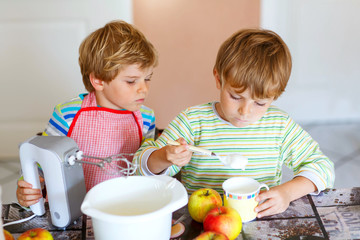 Two little kid boys baking apple cake indoors