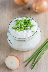 Quark mit Schnittlauch und Zwiebeln steht auf einem Holzbrett.