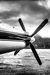 Seaplane nose and propeller in Alaska wilderness under stormy sky. Black and white