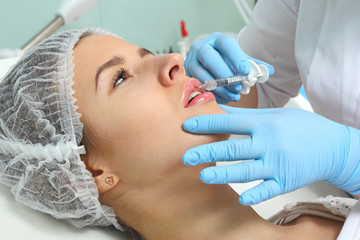 Fototapeta premium Beautiful woman gets an injection in her lips.