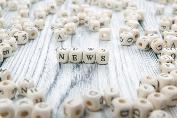 Four wooden blocks with word news written on.