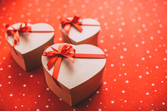 Gifts heart with red ribbon on a red background.