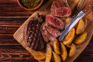 Grilled steak with potato wedges, salsa and spices.