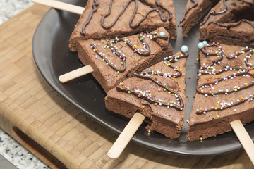 Artisan chocolate cake served on triangle shape on a black dish on a domestic kitchen