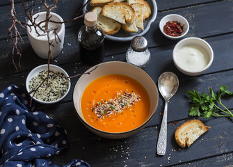 Roasted pumpkin soup in a ceramic bowl on dark wooden surface