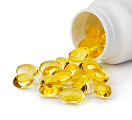 Soft gels pills with Omega-3 oil spilling out of pill bottle close-up isolated on a white background.