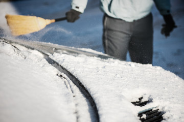 Transportation, winter, weather, people and vehicle concept - woman cleaning snow from her car with...
