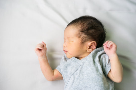 Asian newborn baby lying and crying in his bed