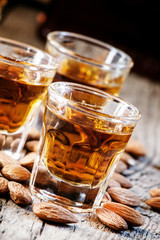 Italian amaretto liqueur with dry almonds on the old wooden back