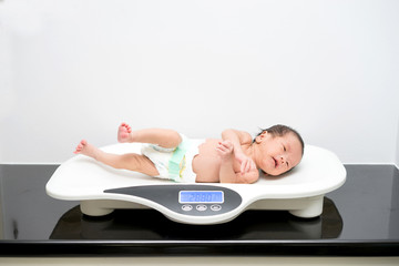 Asian newborn baby laying on the scales © alice_photo