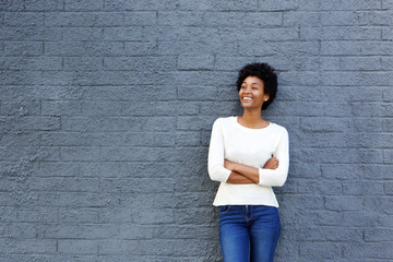 Happy african woman standing against a gray wall