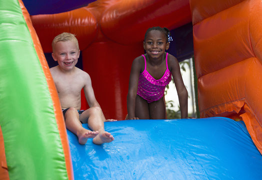 Happy kids sliding down an inflatable bounce house
