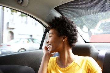 Happy african woman in a car talking on cellphone