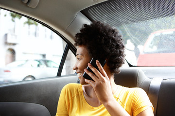 African woman on back seat of car making a phone call