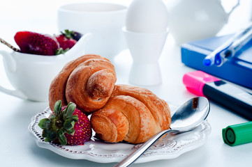breakfast  croissant  and notebook   on a white table