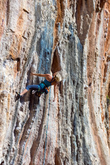 Blond Female Climber ascending Vertical Orange Rock