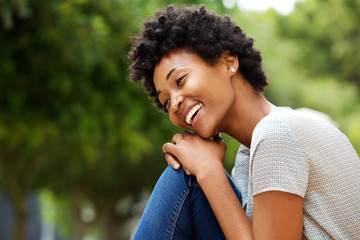 Cheerful young african woman sitting outdoors