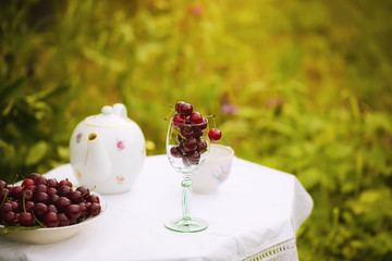 summer background cherry in a glass on a table in the garden, rustic style