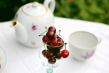 summer background cherry in a glass on a table in the garden, rustic style