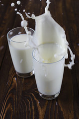 Pouring milk with cookies in the shape of a heart on a wooden background