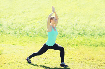 Young woman doing stretching exercises on grass in summer day
