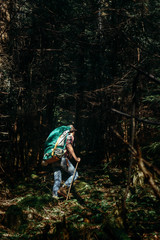 stylish hipster traveler walking in sunny forest in the mountain