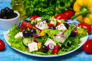 Greek salad with fresh vegetables, feta cheese and black olives on a wooden background