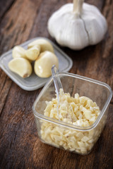 Chopped garlic place inside a plastic container on a wooden background