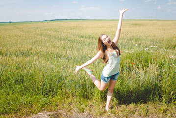 Fototapeta premium Joyful girl in green field with open arms dancing