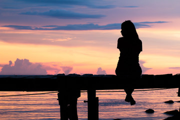 Lonely woman sitting on a wooden bridge sunset.are Lonely. style abstract shadows.silhouette