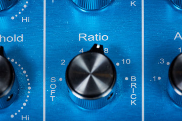 Black ratio knob on blue audio mixing console