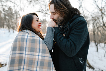 Fototapeta premium Cute young hipster man and pregnant mom having fun in winter park on a sunset hugging each other and smiling 