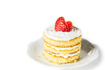 MIni sponge cake with cream and strawberries for Valentines day on white plate. Selective focus.