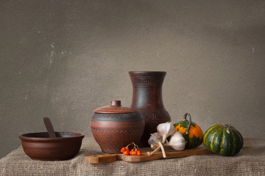 Still life in a rustic style: a set of pottery, pumpkin and garlic