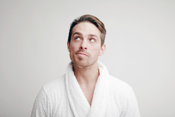 Emotions. Portrait of a Man with a puzzled face in bathrobe - obrazy, fototapety, plakaty