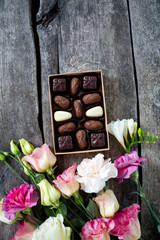 bouquet of beautiful flowers and chocolate on wooden surface