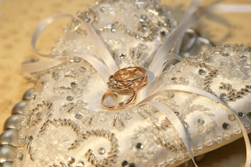 Wedding rings lie on a beautiful embellished rhinestone pillow