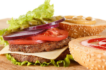 Traditional American cheeseburger. Meat, bun and vegetables close up