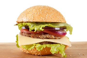 Traditional American cheeseburger. Meat, bun and vegetables close up
