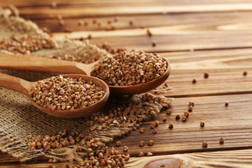 Buckwheat seeds in wooden spoon on a brown wooden table