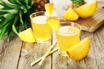 Glasses of pineapple juice on a grey wooden table