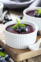 Delicious blueberry mousse in bowls on grey wooden table