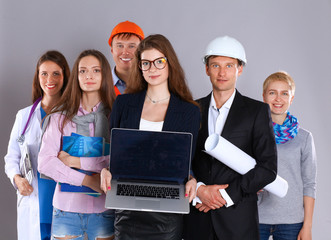 Smiling businesswoman with laptop  and group of industrial workers