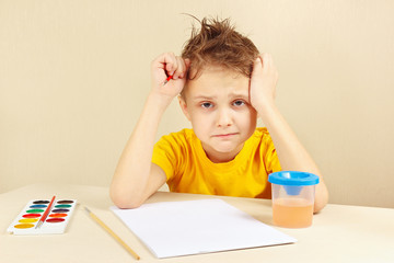 Little preoccupied artist in a yellow shirt is thinking what to draw