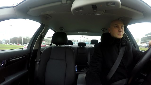 Young man texting and looking at his smartphone while driving a car, putting other drivers in harm's way and jeopardy with his style of reckless and irresponsible driving. View from windscreen.